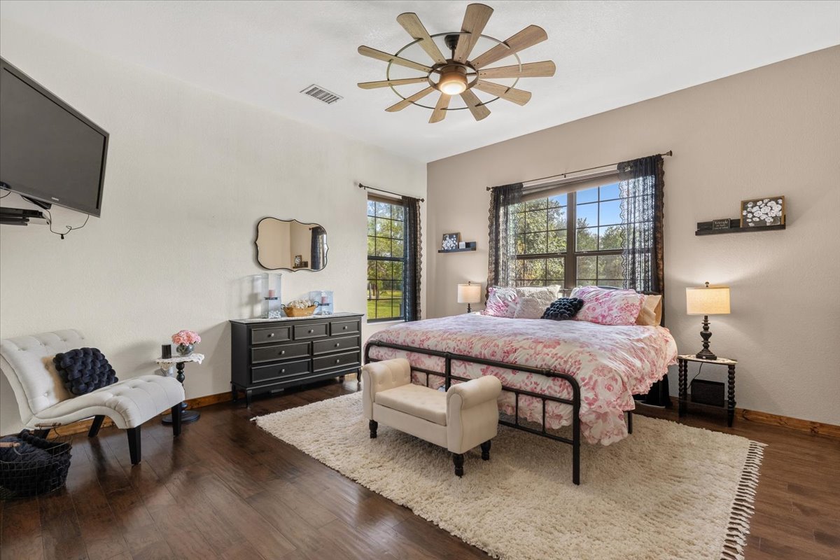 175 Wilson Road Elgin, TX 78621 - Photo 23 of 40 Another oversized guest room! You can comfortably fit a king-sized bed in here, a reading chair, and multiple dressers without feeling cramped at all. The dark hardwood floors carry through here as well, and large windows give you bright, peaceful views of the surrounding acreage.