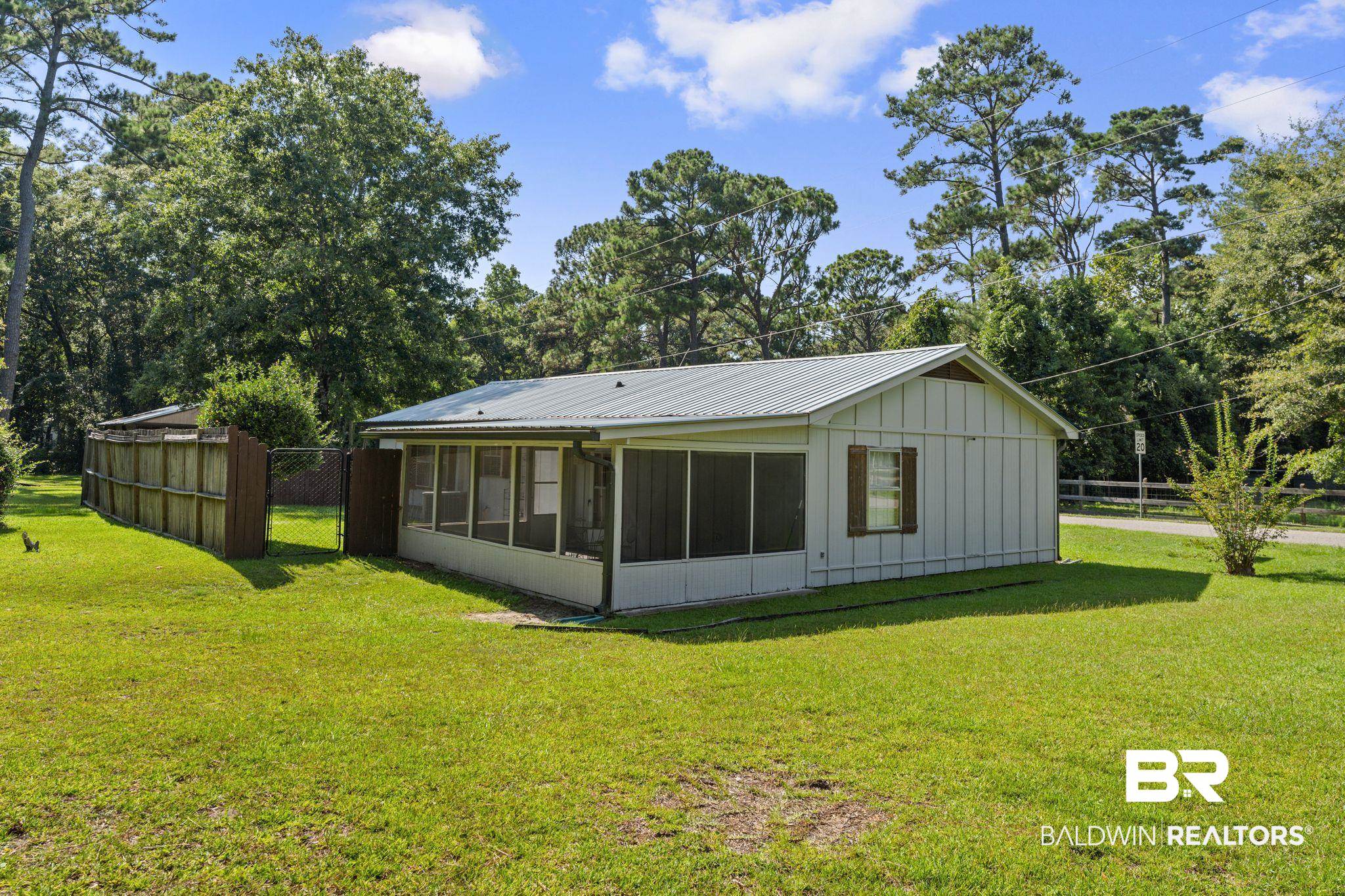 14095 Riverside Drive Foley, AL 36535 - Photo 25 of 30 Back of property featuring a sunroom, a metal roof, view of wooded area, and board and batten siding