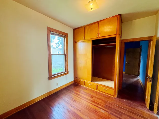 a view of an empty room with window and wooden floor