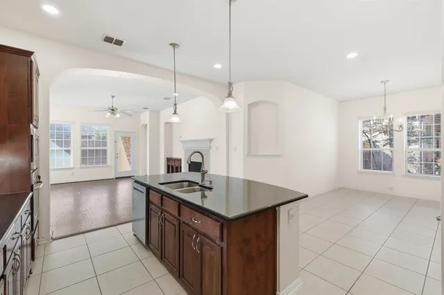 a kitchen with stainless steel appliances granite countertop a stove a sink a refrigerator and white cabinets with wooden floor