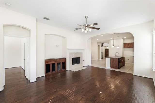 an empty room with wooden floor chandelier fan and windows