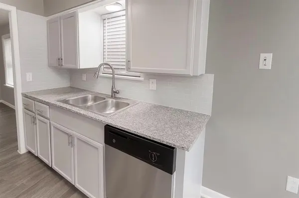 a kitchen with granite countertop white cabinets and a sink