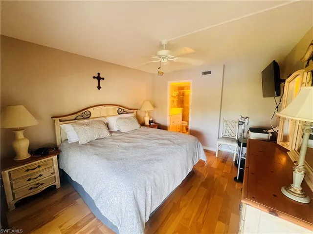 a bedroom with a bed a mirror on the dresser and a chandelier