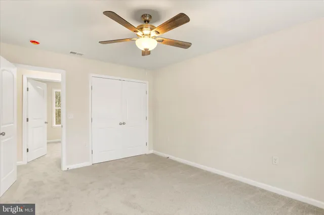 an empty room with a ceiling fan and a window