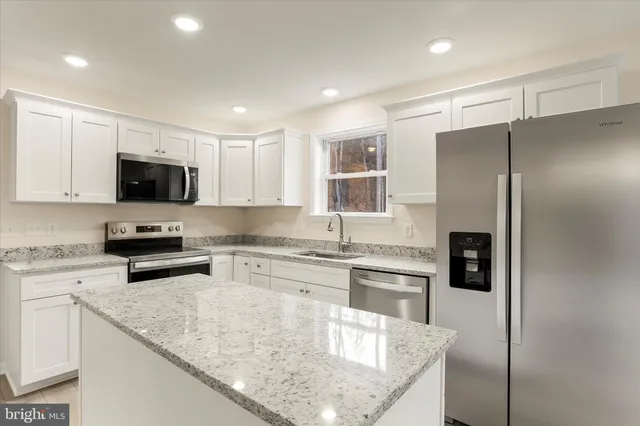 a kitchen with stainless steel appliances granite countertop a refrigerator a stove top oven a sink and dishwasher