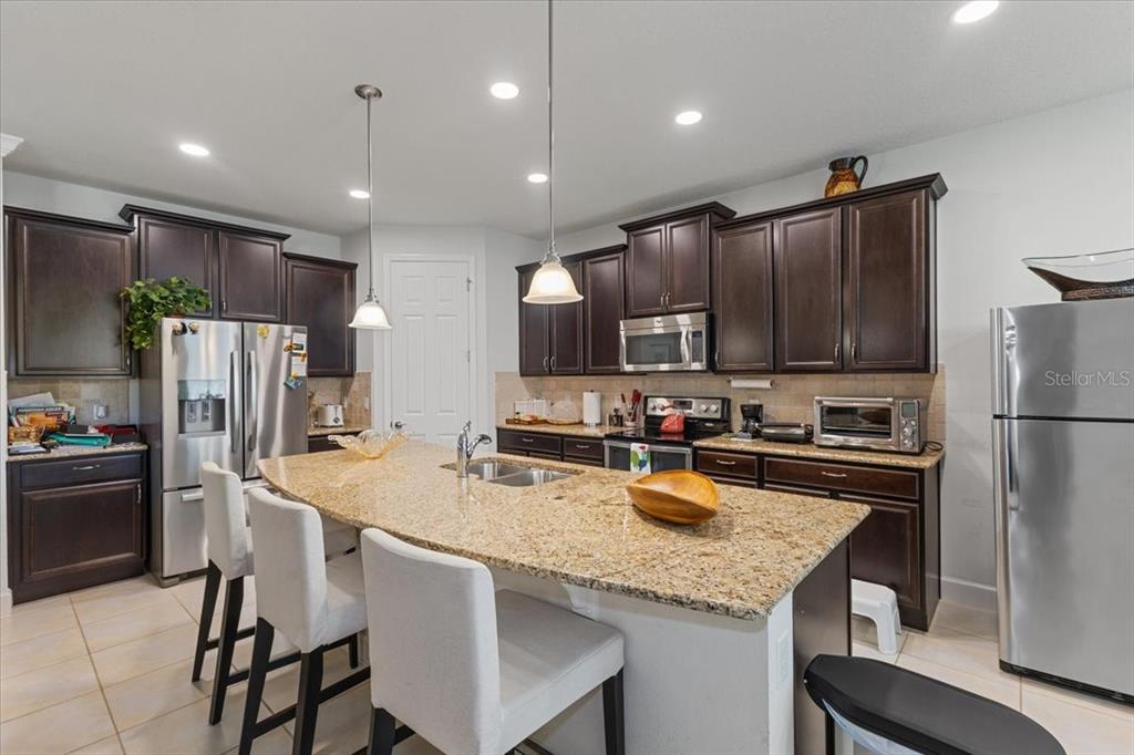 7180 Beek Street Windermere, FL 34786 - Photo 5 of 33 a kitchen with stainless steel appliances granite countertop a refrigerator a stove a sink a microwave and white cabinets