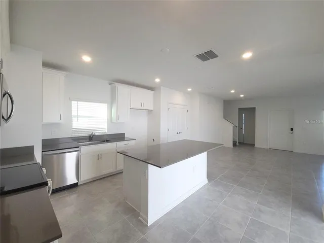 a view of a kitchen with kitchen island white cabinets and wooden floor