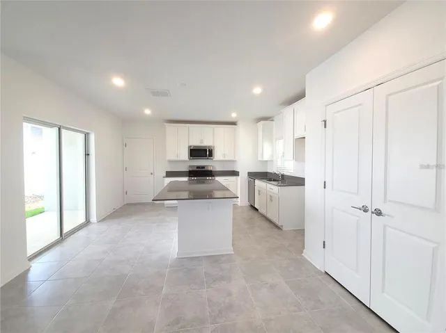 a kitchen with a refrigerator and white cabinets