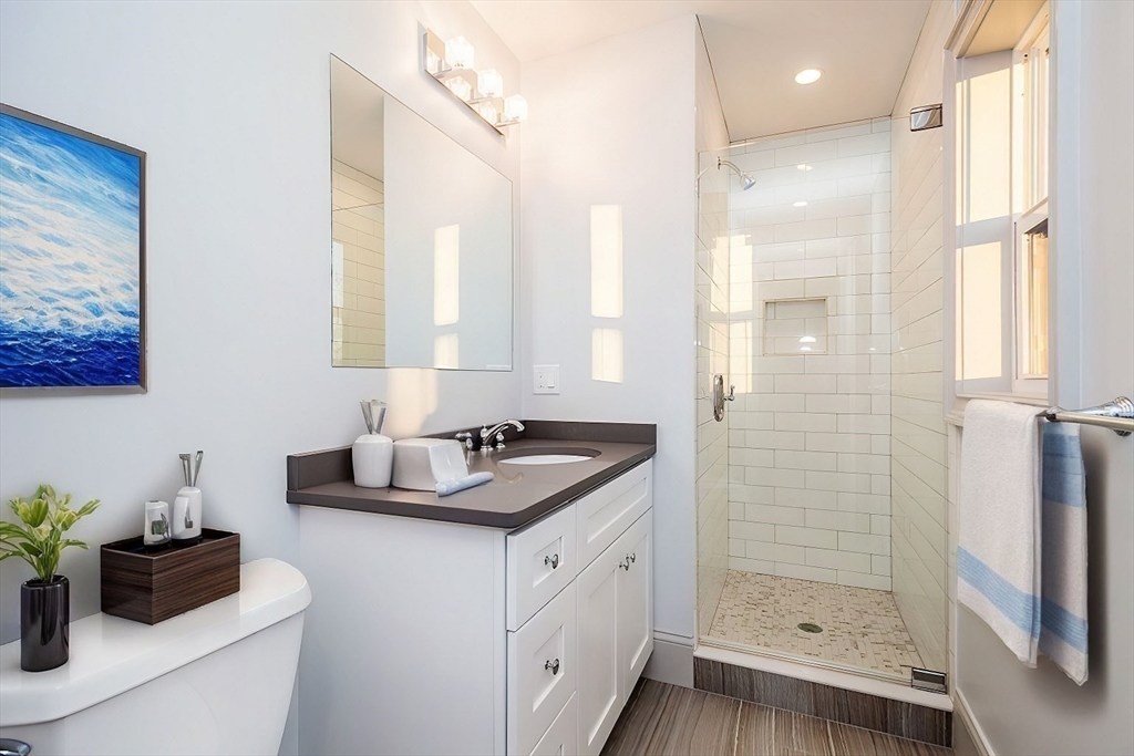 53 River Street, Unit 53 Boston, MA 02126 - Photo 7 of 25 a bathroom with a granite countertop sink a shower and a mirror