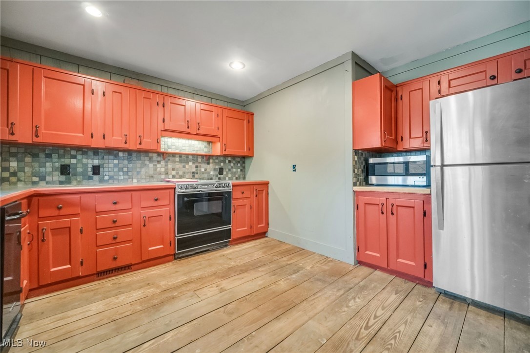 18060 Falling Leaves Road Strongsville, OH 44136 - Photo 11 of 43 Kitchen with stainless steel appliances, light countertops, light wood-style flooring, and decorative backsplash