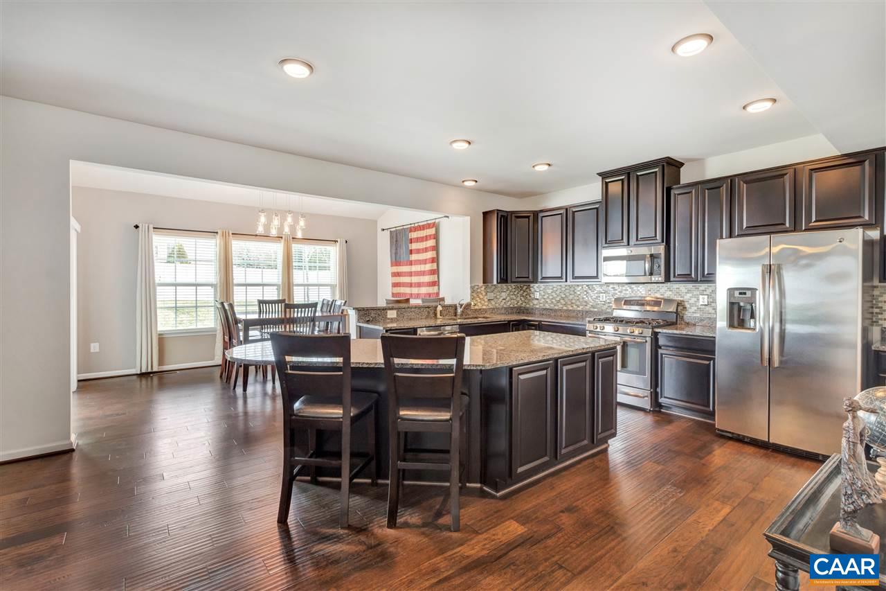 365 Ridgemont Road Ruckersville, VA 22968 - Photo 4 of 50 a kitchen with stainless steel appliances granite countertop a stove a refrigerator a microwave a dining table and chairs with wooden floor