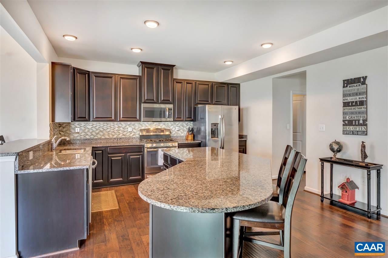 365 Ridgemont Road Ruckersville, VA 22968 - Photo 7 of 50 a open kitchen with stainless steel appliances granite countertop a stove top oven a refrigerator a sink and a dining table with white cabinets