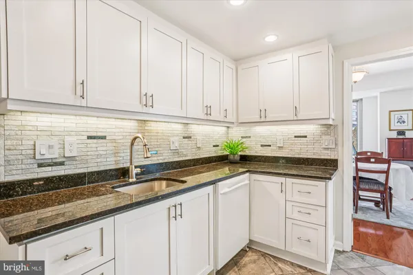 a kitchen with granite countertop a sink and white cabinets