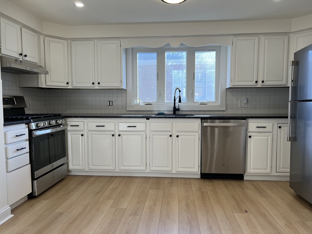 262 Nevada Street, Unit A Newton, MA 02460 - Photo 2 of 34 a kitchen with granite countertop a stove a sink and dishwasher with white cabinets