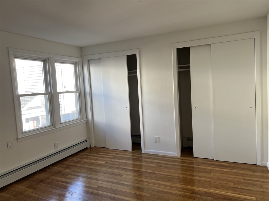 262 Nevada Street, Unit A Newton, MA 02460 - Photo 22 of 34 an empty room with wooden floor and windows