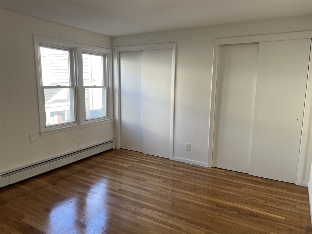 262 Nevada Street, Unit A Newton, MA 02460 - Photo 25 of 34 an empty room with wooden floor and windows