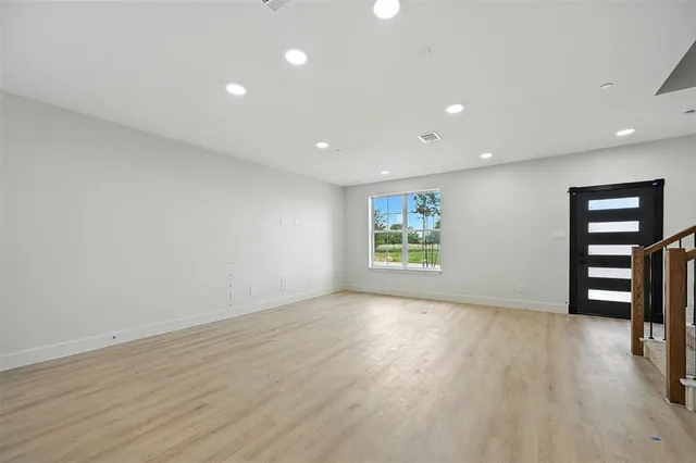 an empty room with wooden floor closet and windows