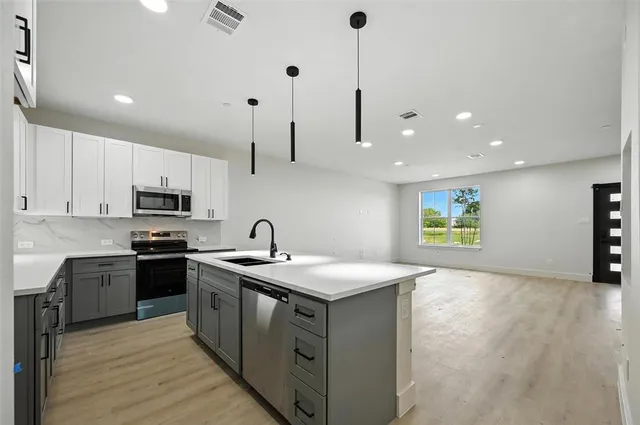 a kitchen with stainless steel appliances granite countertop a sink a stove and a refrigerator