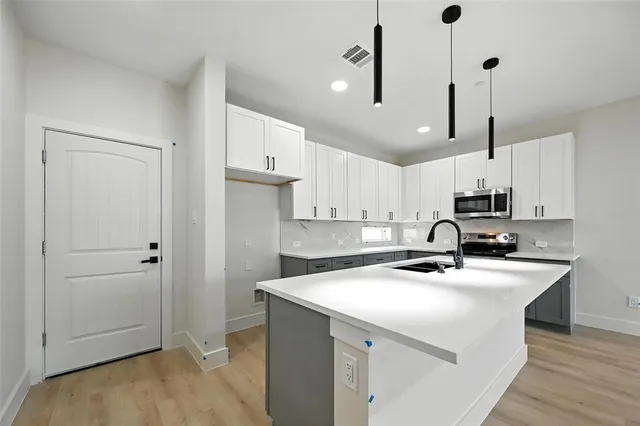 a kitchen with stainless steel appliances a sink a stove a refrigerator a center island and cabinets