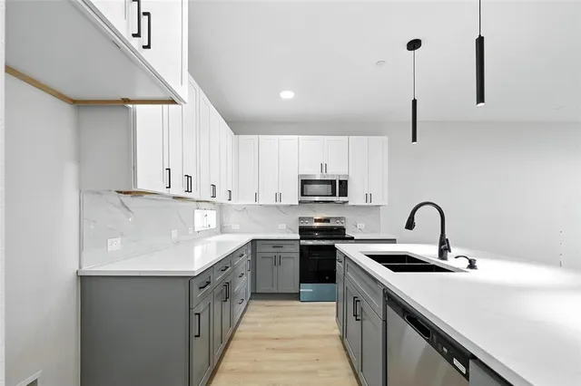 a kitchen with stainless steel appliances a sink a stove top oven a counter space and cabinets