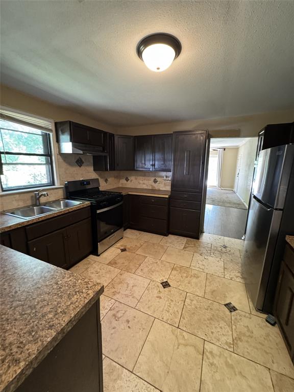803 Ripley Avenue Ennis, TX 75119 - Photo 11 of 40 Kitchen featuring dark wood-finish cabinetry, stainless steel appliances, stone-look countertops, and a decorative tile backsplash