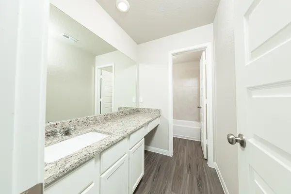 a bathroom with a granite countertop sink a toilet and shower
