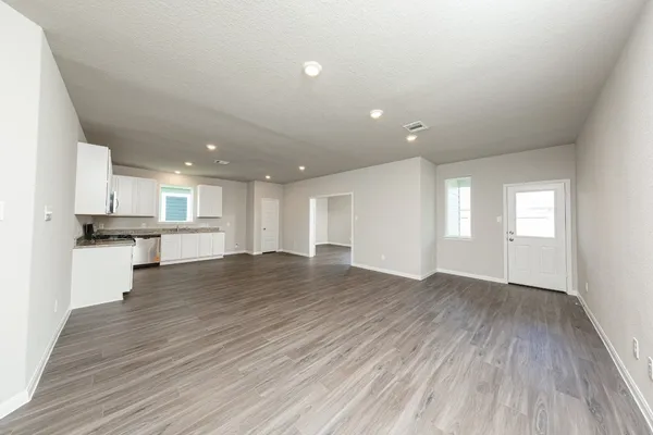 a view of kitchen and empty room with wooden floor