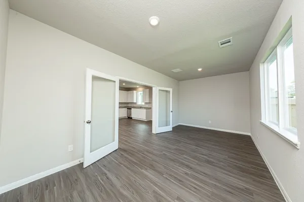 an empty room with wooden floor and windows