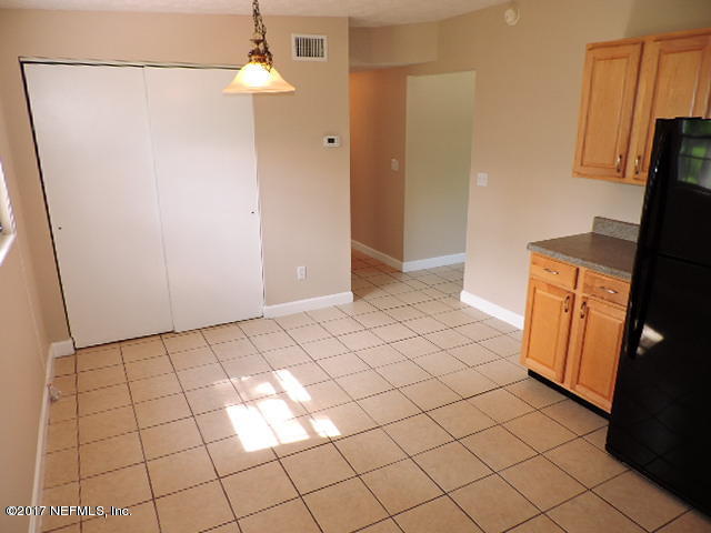 410 Skate Road Atlantic Beach, FL 32233 - Photo 8 of 31 a view of a refrigerator in kitchen and an empty room in wooden floor