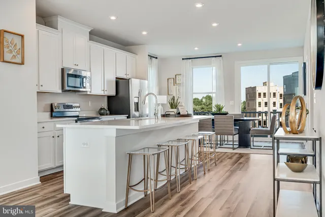 a kitchen with stainless steel appliances granite countertop a stove top oven a sink dishwasher a refrigerator and white cabinets with wooden floor