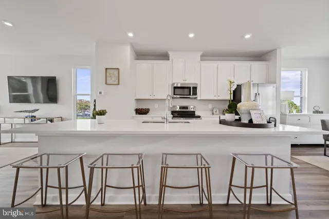 a kitchen with stainless steel appliances a white table chairs refrigerator and microwave