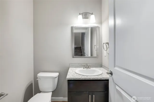 a bathroom with a granite countertop sink and a toilet