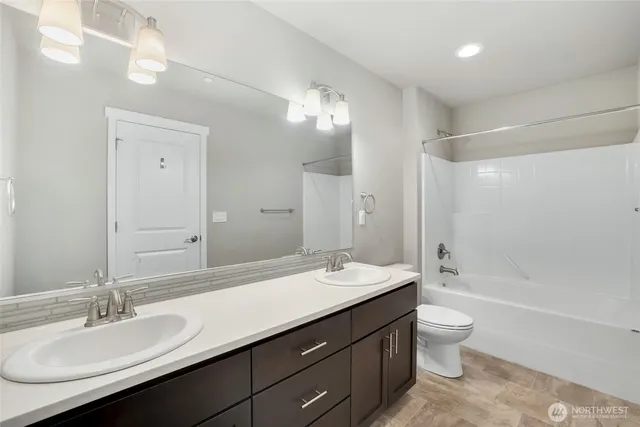 a bathroom with a double vanity sink toilet mirror and bathtub