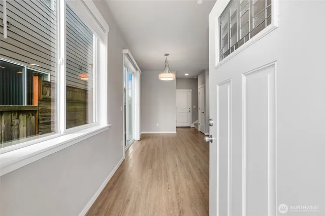 a view of a hallway with wooden floor and a bathroom