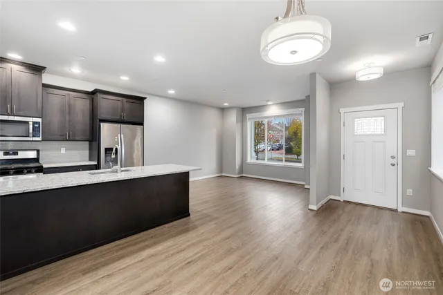 a large kitchen with stainless steel appliances a large counter top and wooden floors