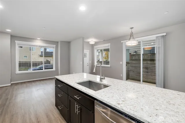 a kitchen with kitchen island a sink wooden floor and a refrigerator