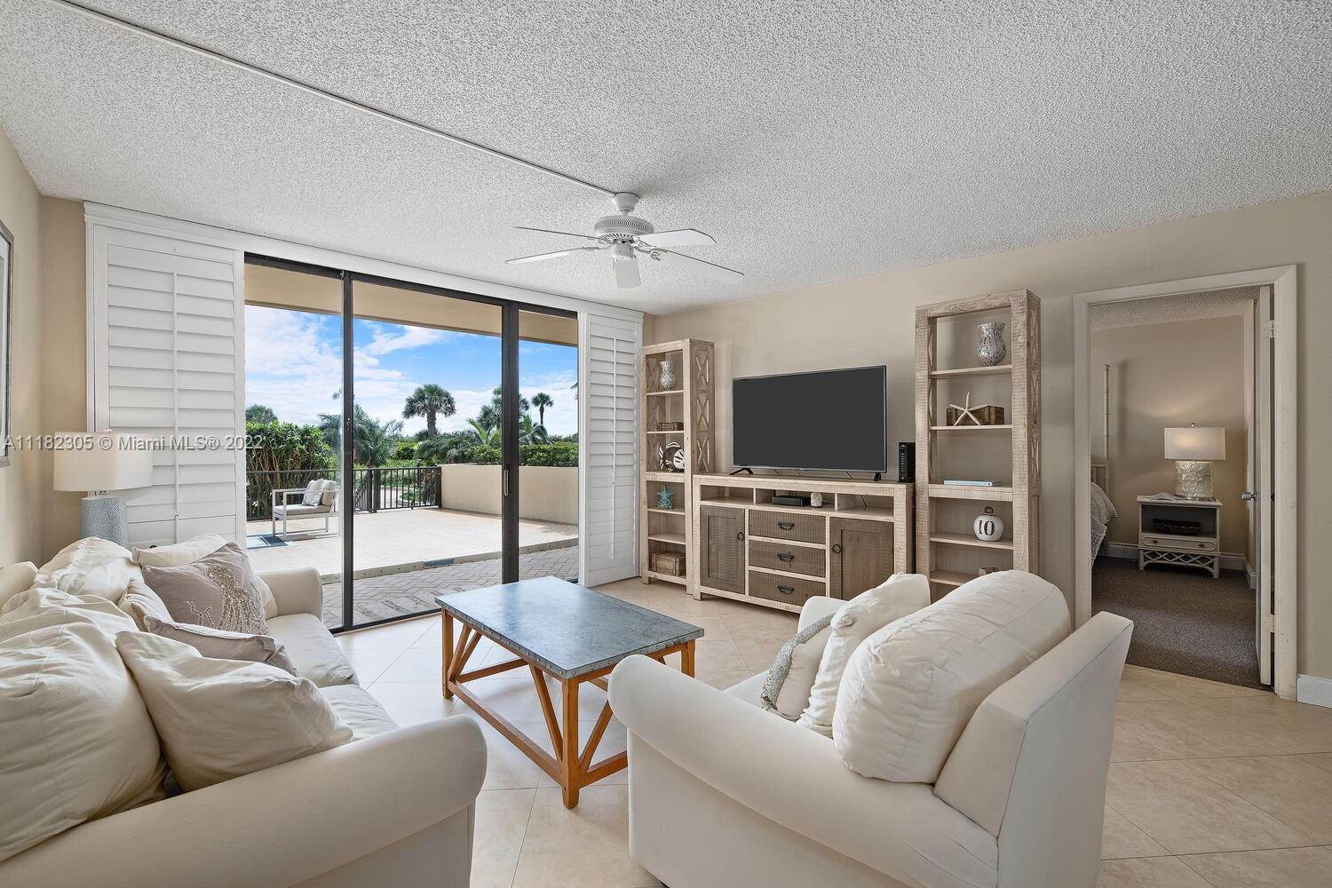 300 Ocean Trail Way, Unit 104 Jupiter, FL 33477 - Photo 2 of 26 a living room with furniture a flat screen tv and a large window
