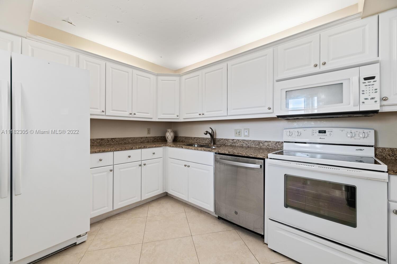 300 Ocean Trail Way, Unit 104 Jupiter, FL 33477 - Photo 5 of 26 a kitchen with granite countertop white cabinets and stainless steel appliances