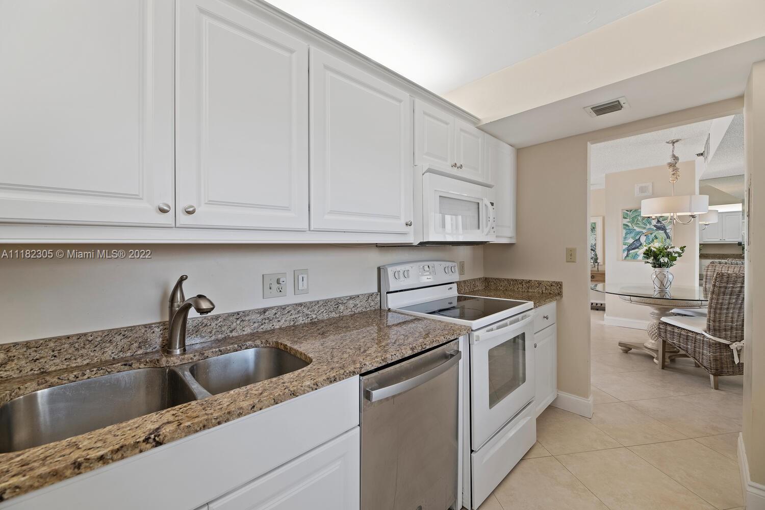 300 Ocean Trail Way, Unit 104 Jupiter, FL 33477 - Photo 7 of 26 a kitchen with white cabinets and white appliances