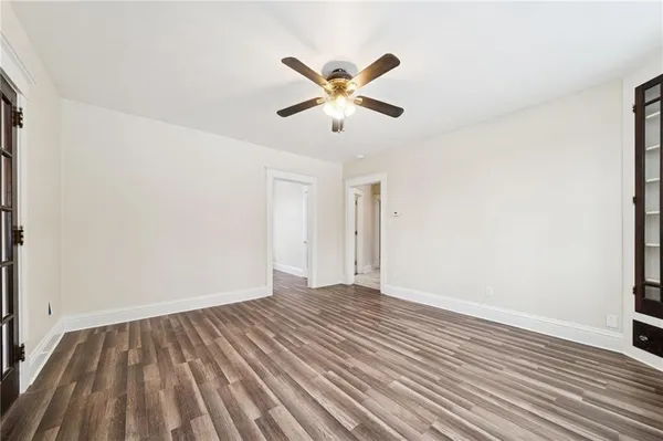 a view of an empty room with wooden floor and a ceiling fan