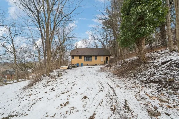 a front view of a house with a yard covered with snow and trees