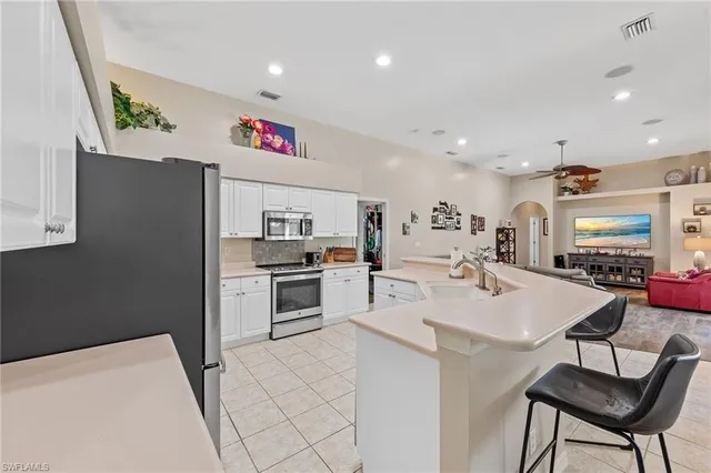 a kitchen with stainless steel appliances kitchen island a table chairs and a refrigerator