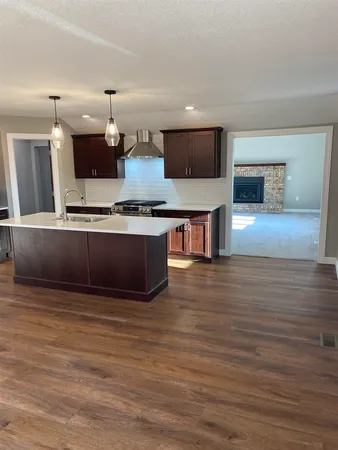 a view of kitchen with stainless steel appliances wooden floor and living room