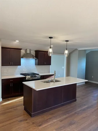 a large kitchen with stainless steel appliances a large counter top and a wooden floors