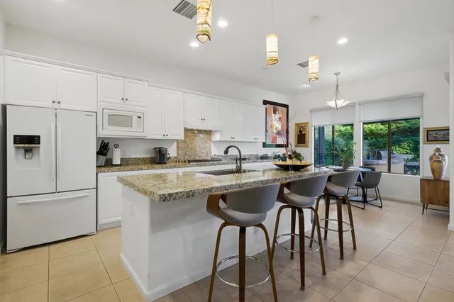 a kitchen with granite countertop white cabinets stainless steel appliances and window