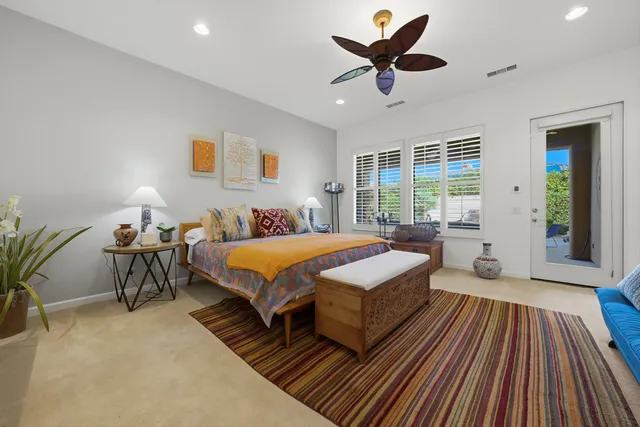 a spacious bedroom with a bed a chandelier and a rug