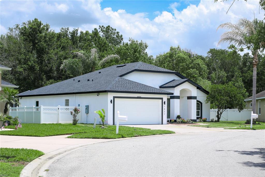 7027 Frascati Loop Wesley Chapel, FL 33544 - Photo 2 of 28 a view of a big house with a big yard and large trees