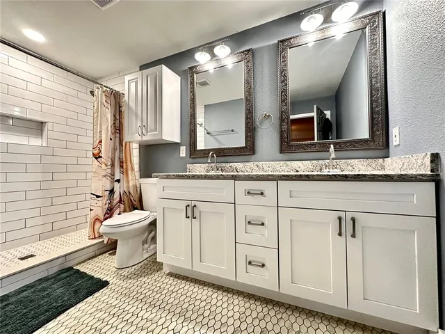 a bathroom with a granite countertop sink mirror vanity and toilet