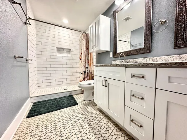 a bathroom with a sink a toilet a mirror and shower