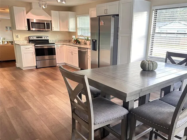 a kitchen with stainless steel appliances kitchen island granite countertop a table chairs microwave and refrigerator